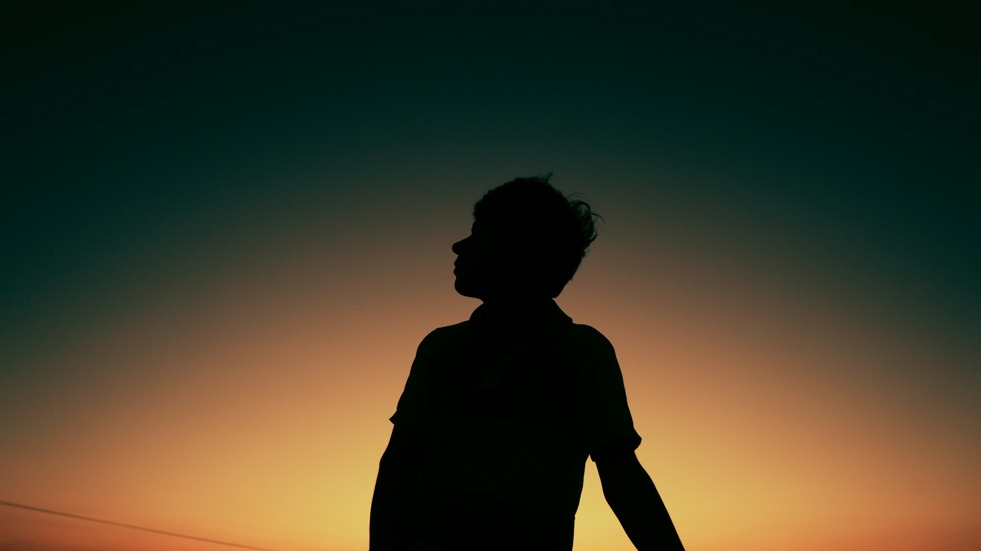 a silhouette of a person holding a surfboard at sunset